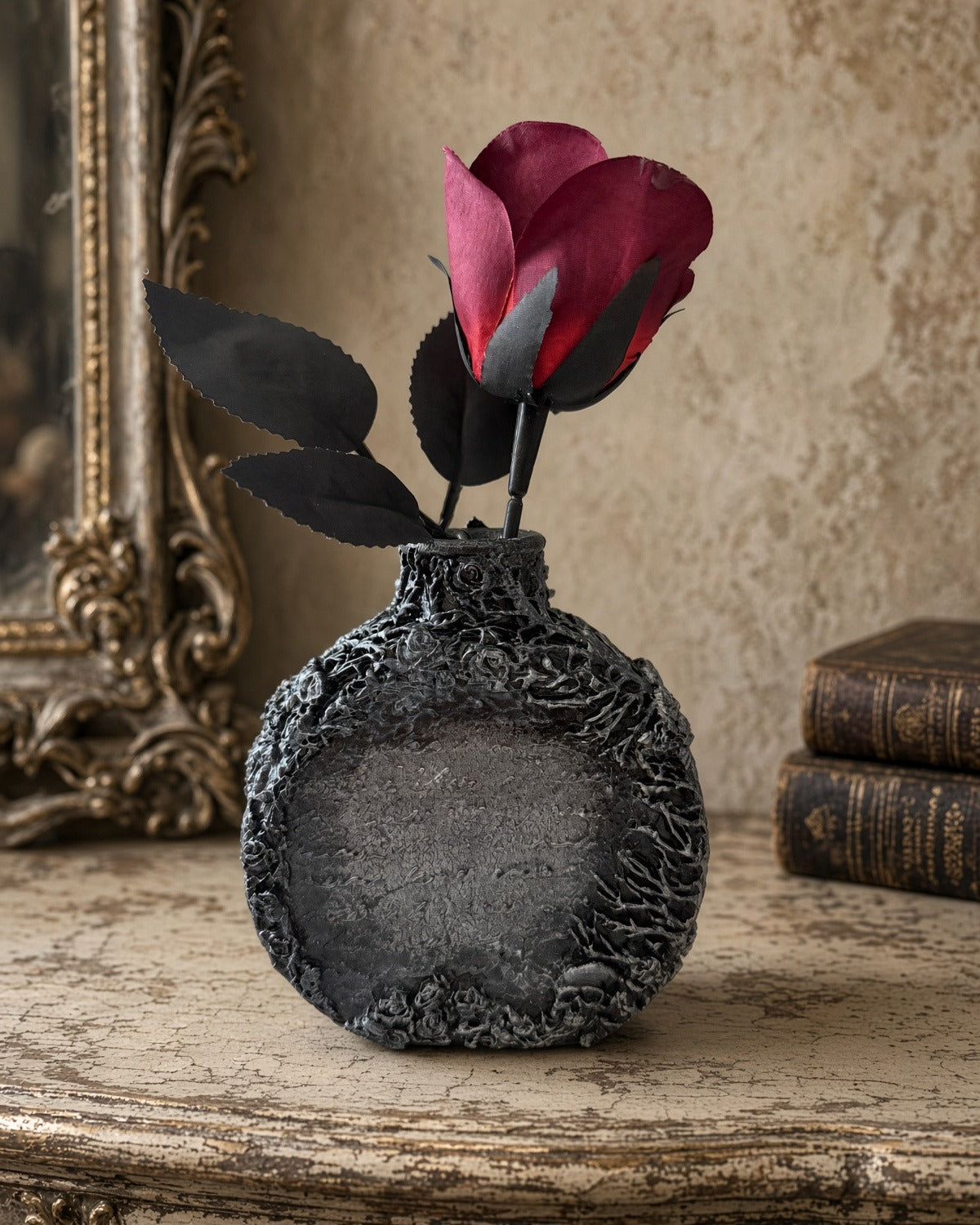 Back of handmade gothic glass bottle with textured relief roses, small skull and center panel, styled with a red rose