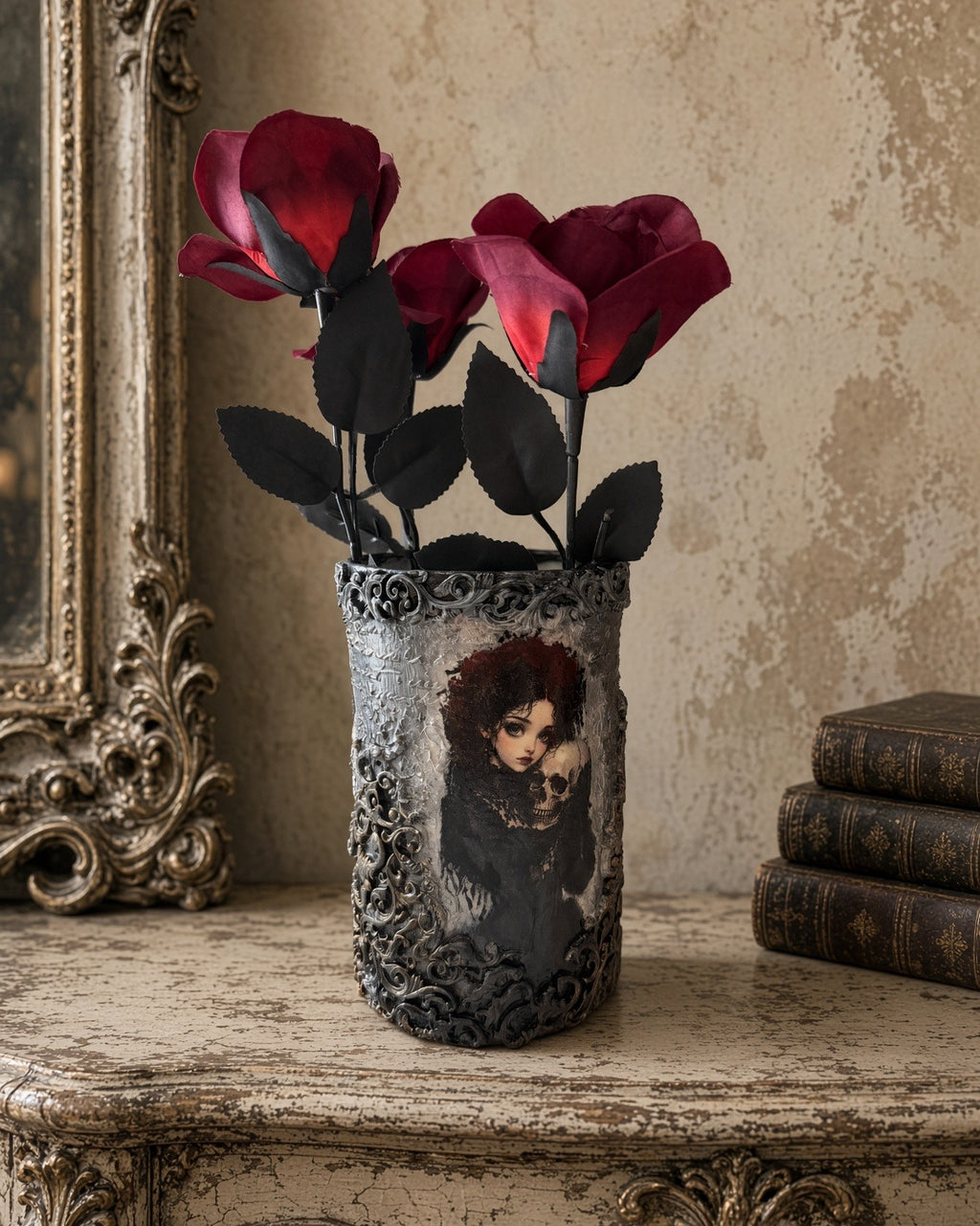 Gothic decoupage glass vase showing a girl holding a small skull, ornate silver relief, red roses, cream vintage table