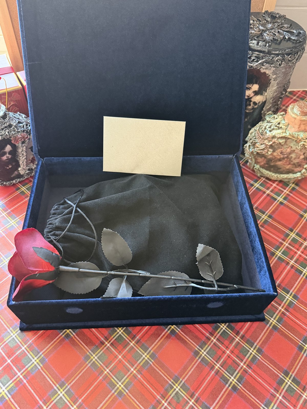 Navy velvet gift box opened with black pouch, metal rose and card